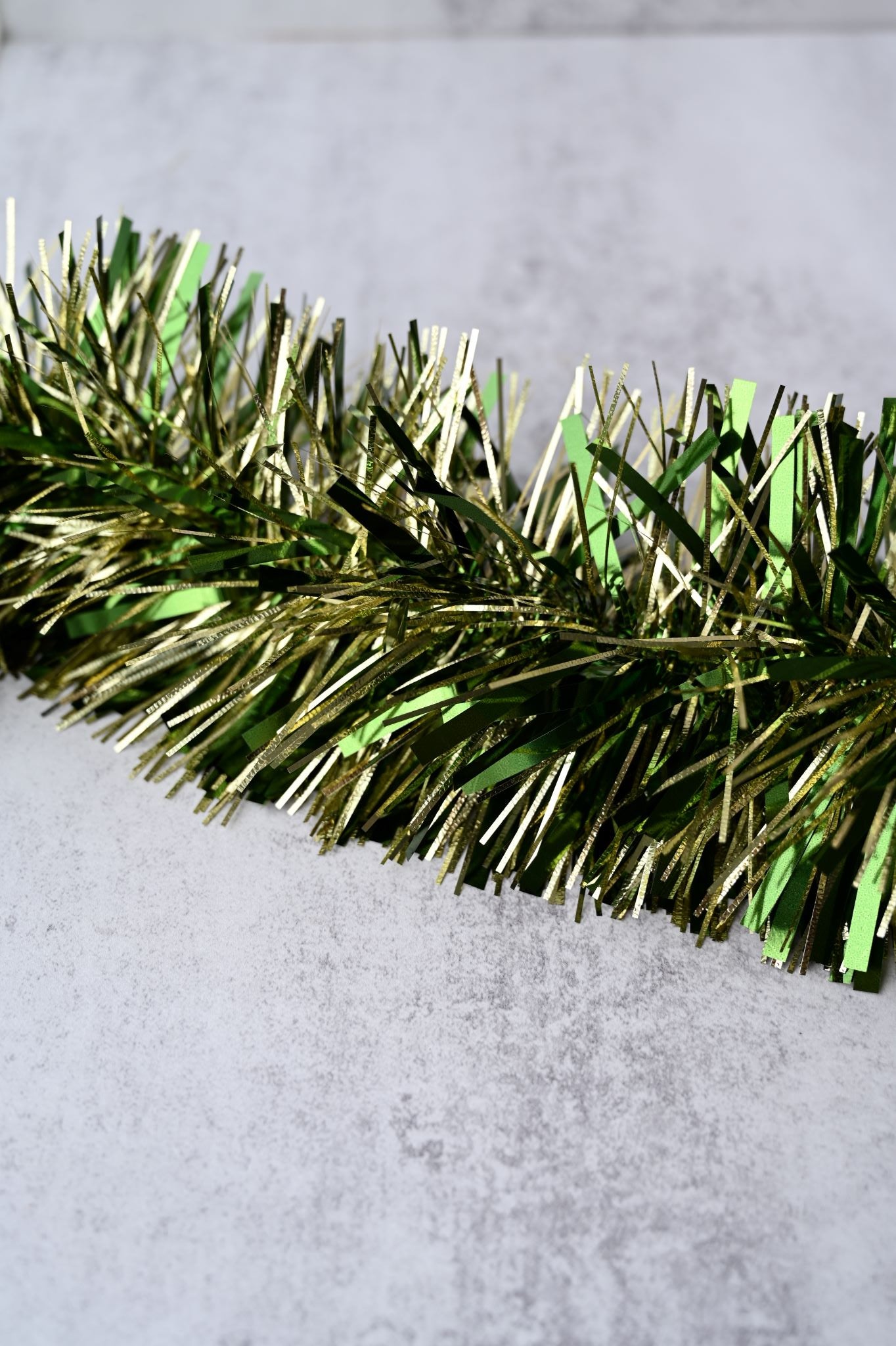 Thick, luxury green and gold embossed Christmas tinsel garland close-up.
