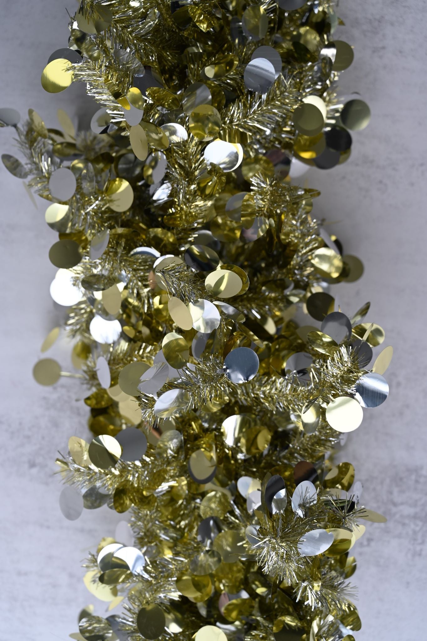 Close-up of thick gold tinsel garland scattered with reflective silver and gold sequins.