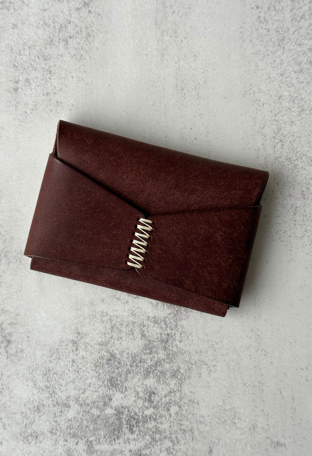 Minimalist handmade leather cardholders in various colours with a unique hand-stitched cross closure.
