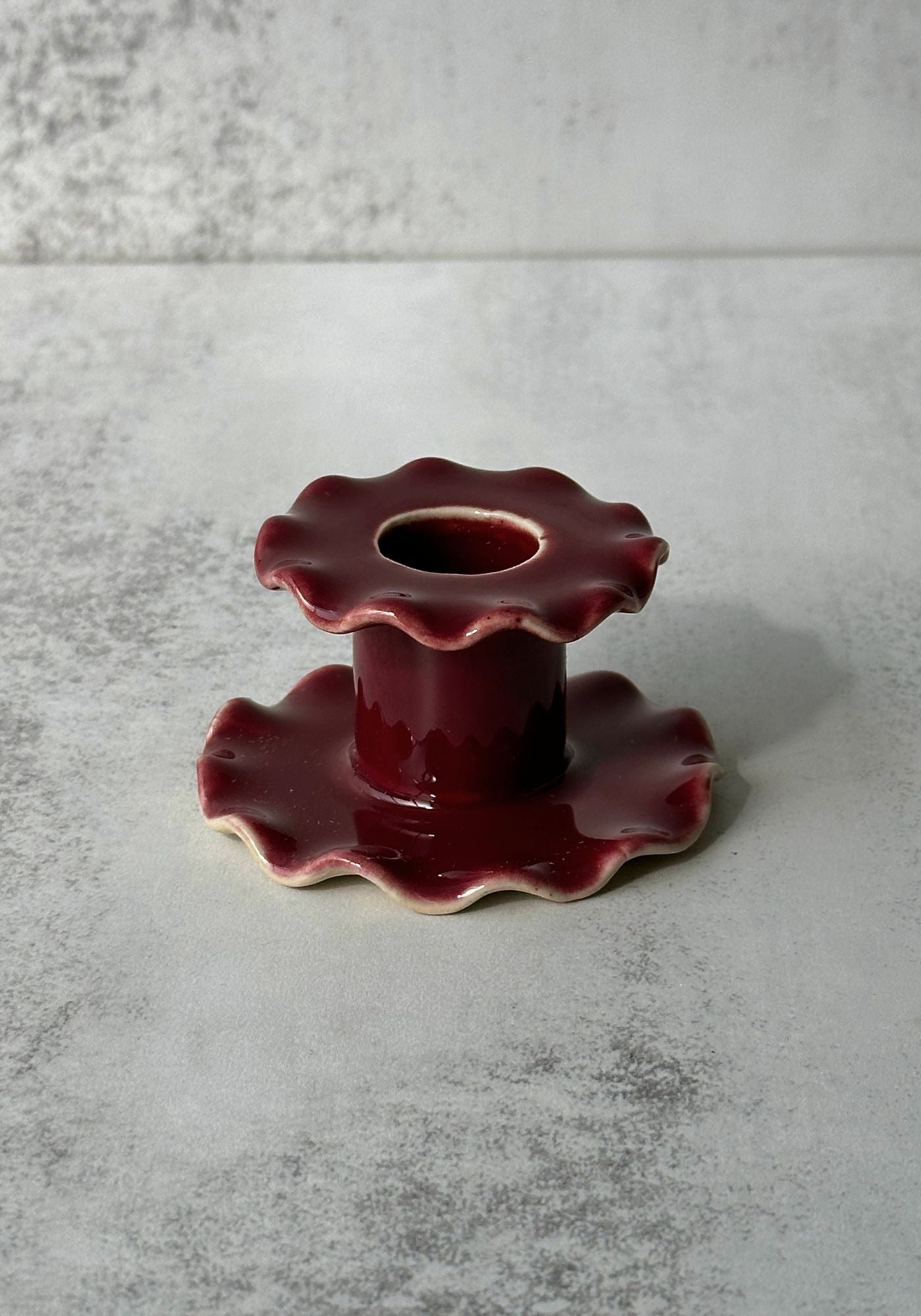 Hand-thrown ceramic candle holders with ruffled edges in blue, pink, and yellow glazes.
