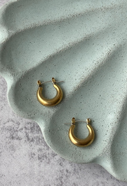 Chunky crescent-shaped brass hoop earrings with a polished 14k gold-plated finish.