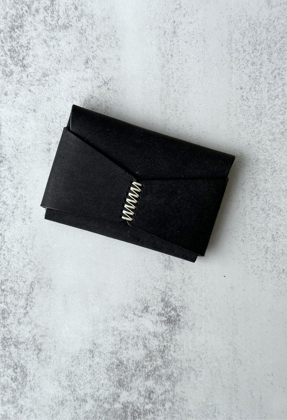 Minimalist handmade leather cardholders in various colours with a unique hand-stitched cross closure.