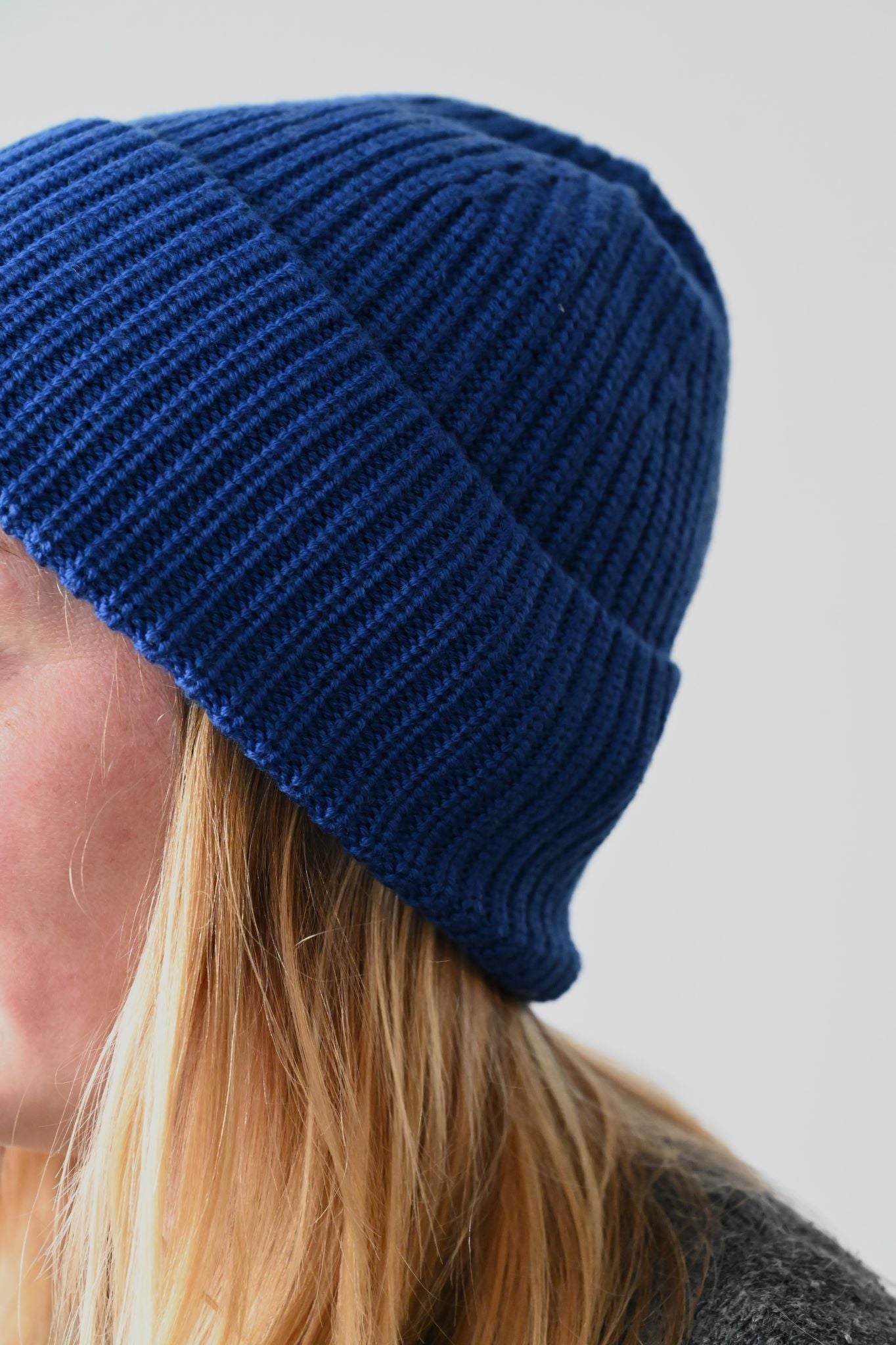 Close-up of a vibrant royal blue chunky ribbed merino wool beanie with folded cuff.