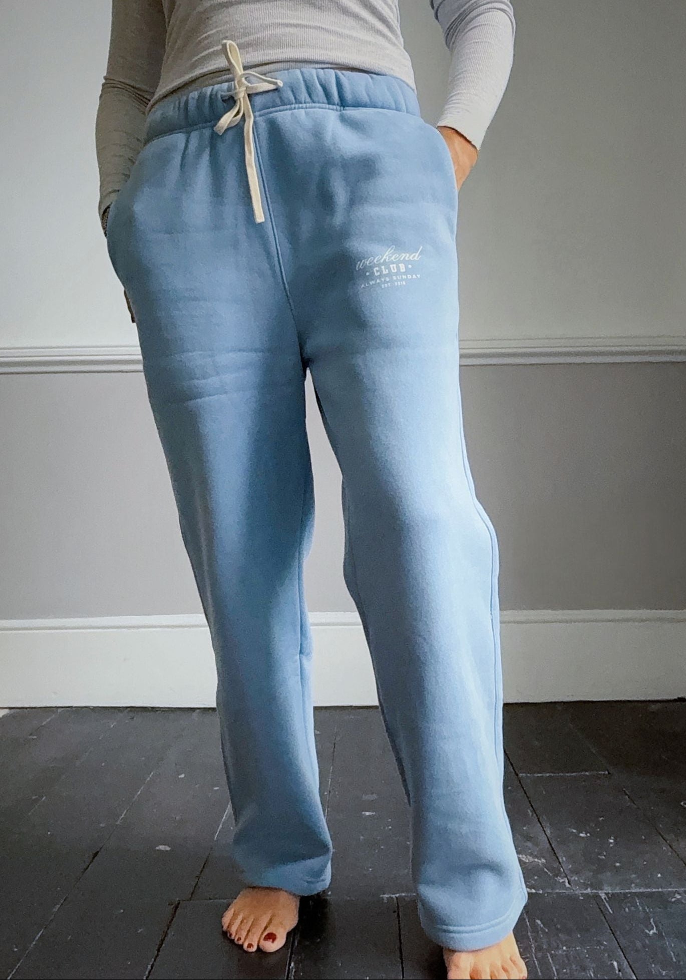 Light blue sweatpants with a brand logo worn by a person against a plain background