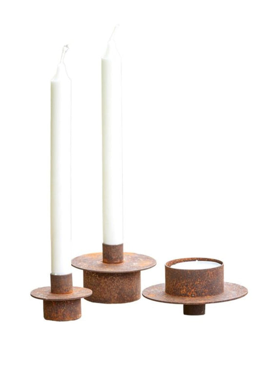 Rusted metal planter candle holder insert with a lit terracotta pillar candle.