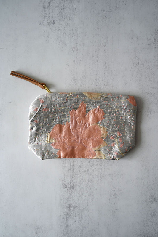 Silver and pink floral jacquard cosmetic pouches with gold hardware and tan zipper pulls.