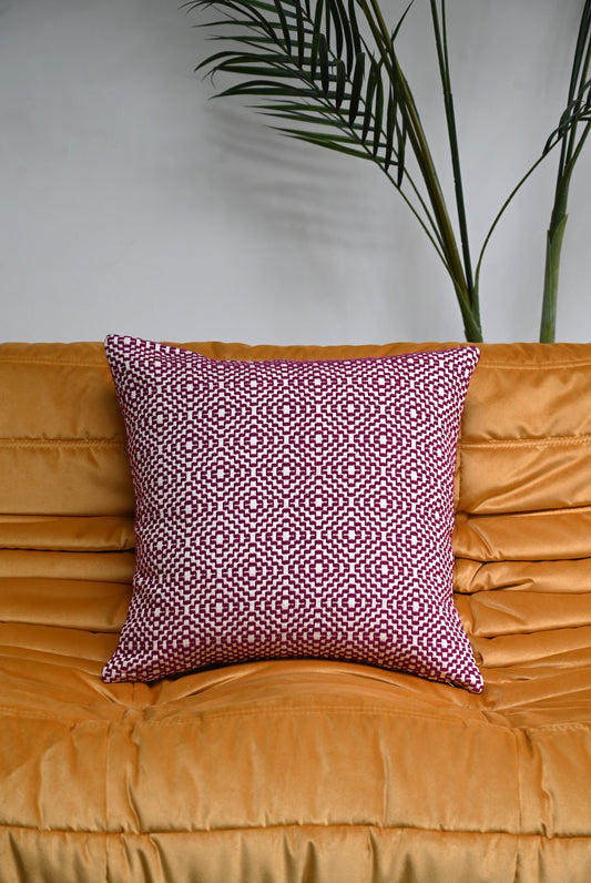 Purple geometric patterned cushion on an orange sofa with a plant in the background