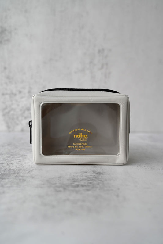 Three ivory packing pouches in graduated sizes with clear windows and black zips.