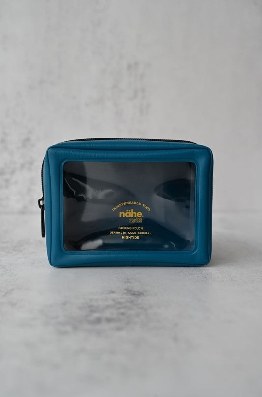 Three indigo blue packing pouches with transparent windows and gold lettering in graduated sizes.