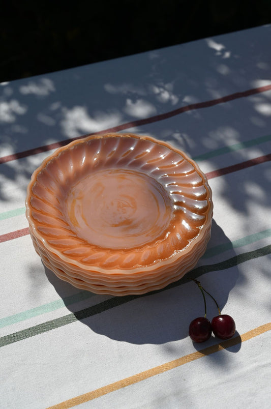 Stack of six iridescent amber carnival glass plates with decorative scalloped and swirled rims.