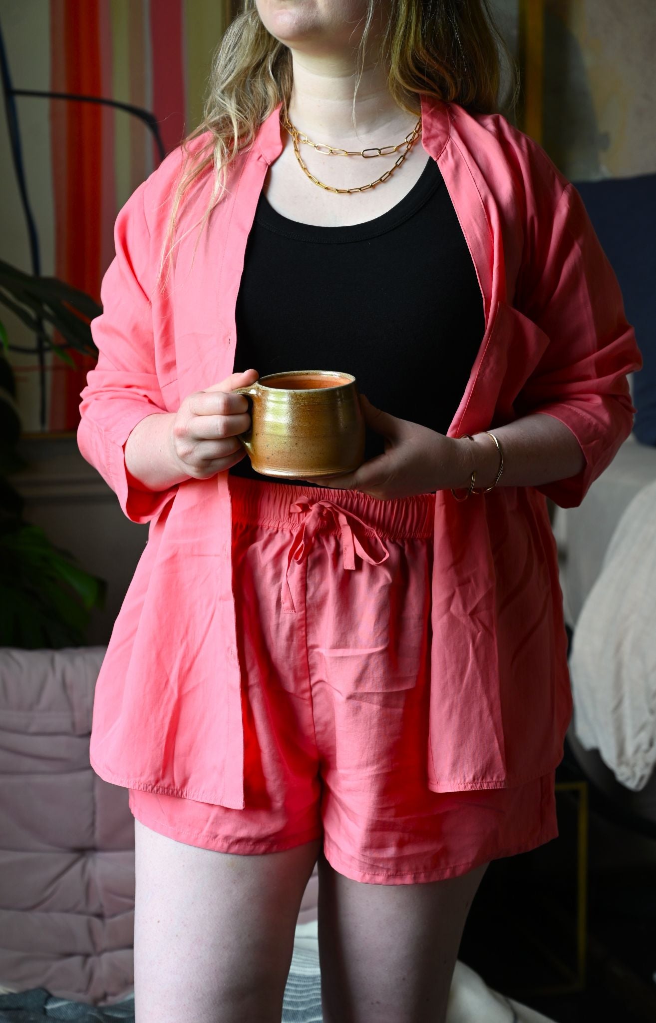 Person wearing a pink outfit holding a gold cup indoors.