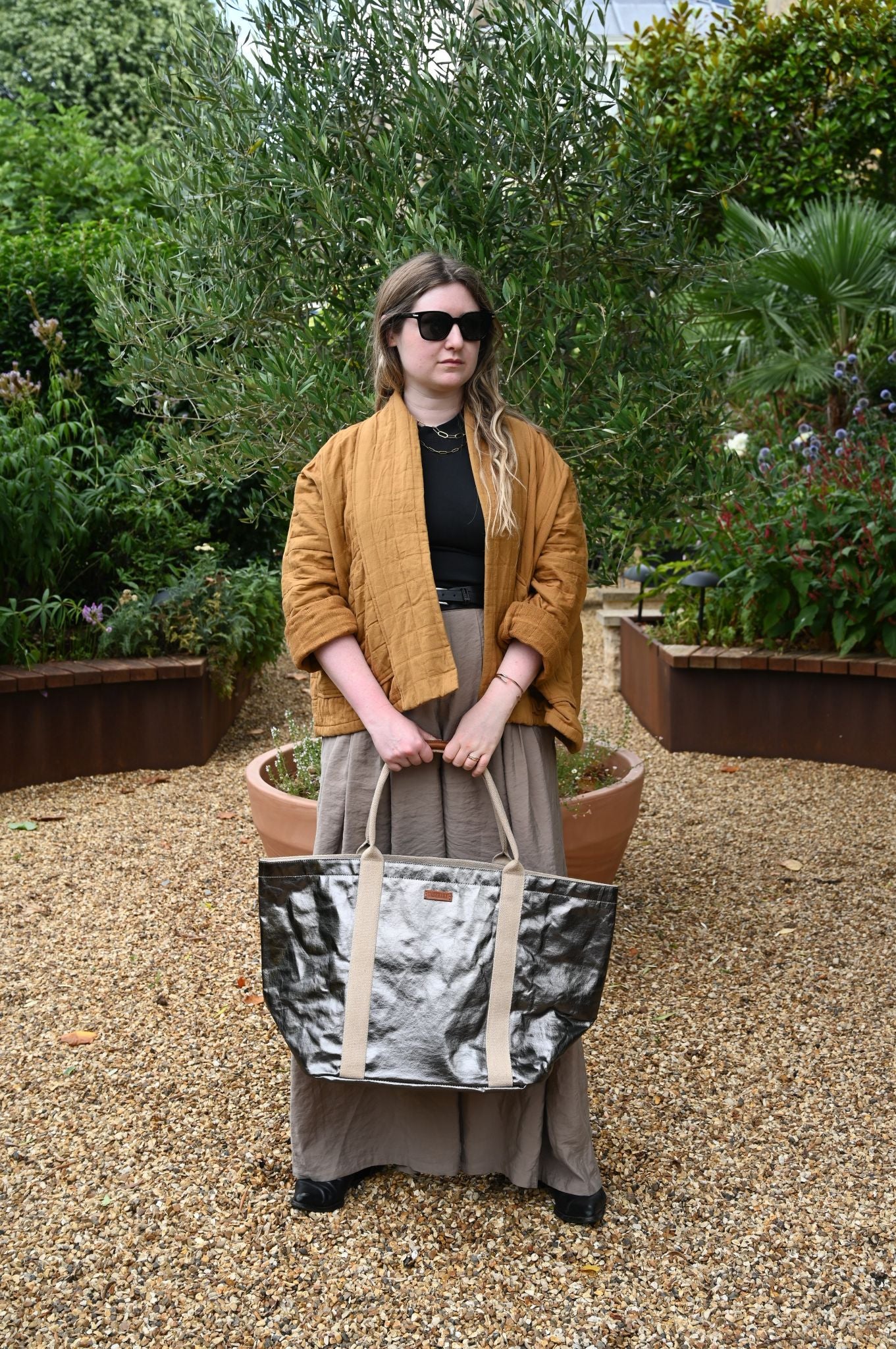 Person holding a patterned bag in an outdoor garden setting