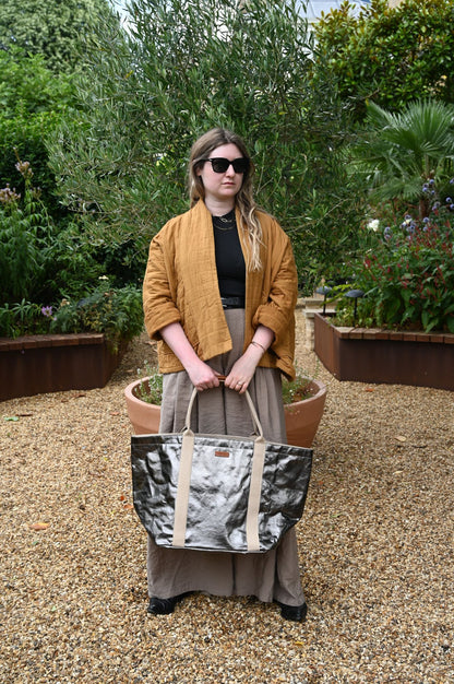 Person holding a patterned bag in an outdoor garden setting