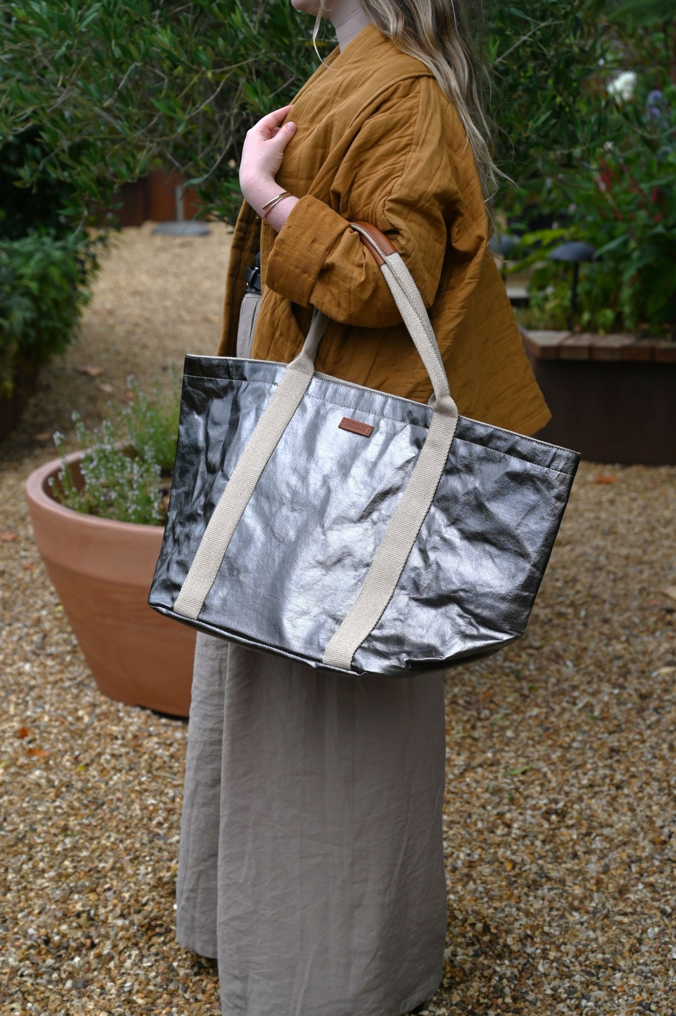 Person holding a silver and beige tote bag outdoors