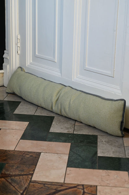 Green door stopper on a tiled floor in front of a white door.