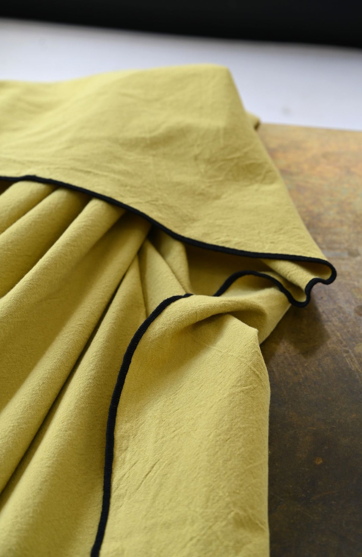 Recycled cotton tablecloth in muted tones with a contrasting black bourdon border stitch.