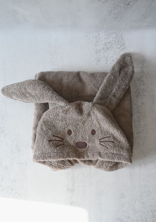 Folded towel shaped like a bunny with ears on a textured surface