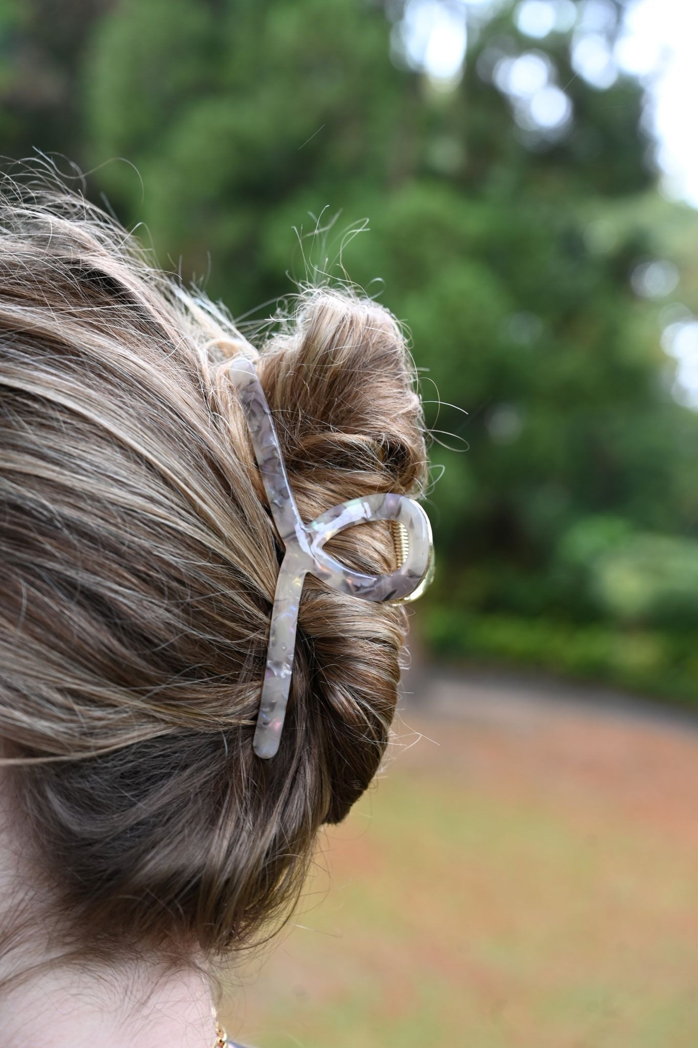 Close-up of a hair bun with a hair clip against a blurred natural background