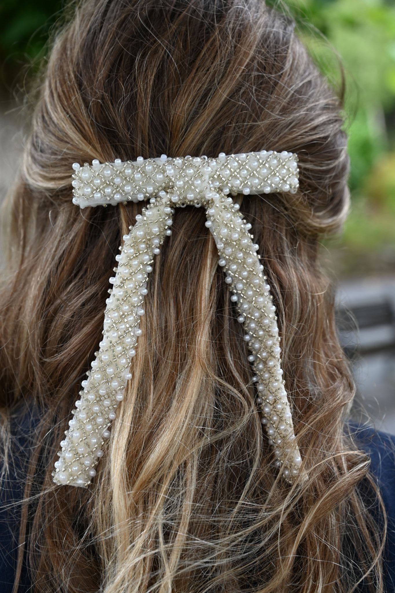 Pearl embellished hair clip in a person's hair with a blurred background