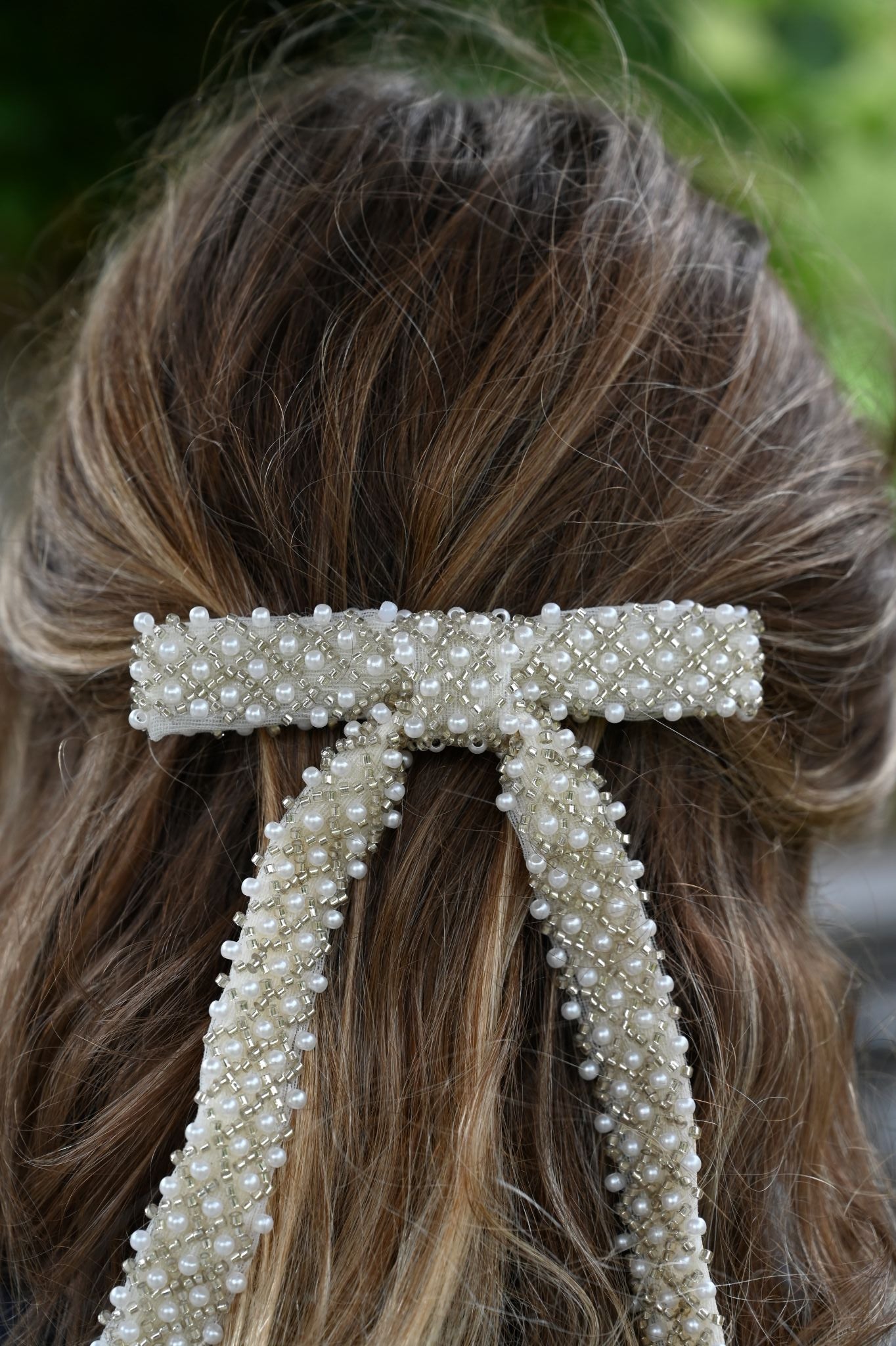 Close-up of a decorative hair clip with pearls in brown hair