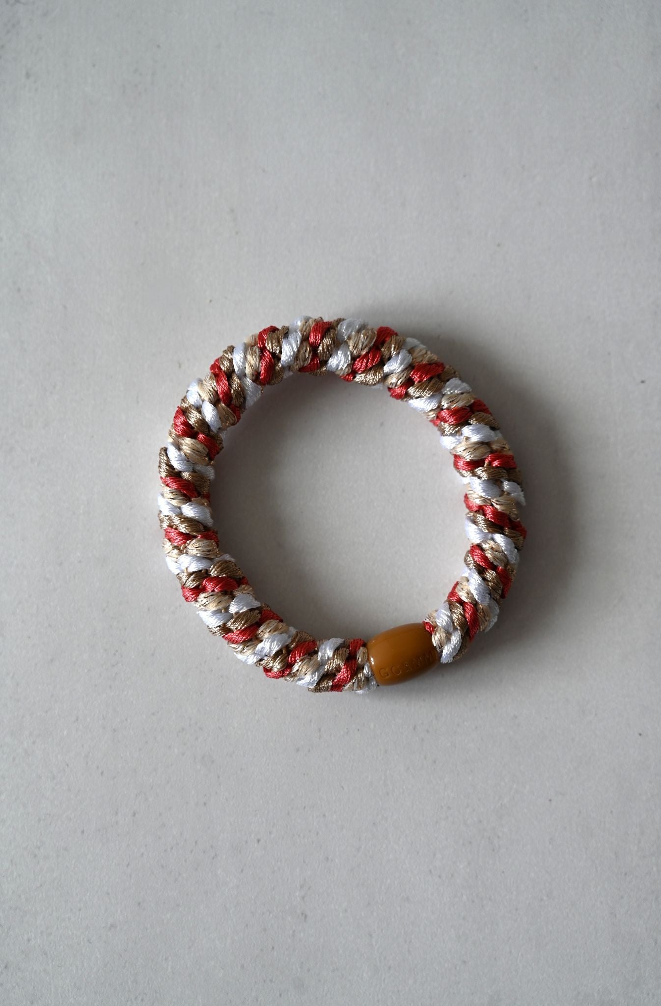 Bracelet with red, white, and brown colors on a gray background