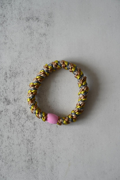 Colorful beaded hair tie with a pink bead on a gray surface