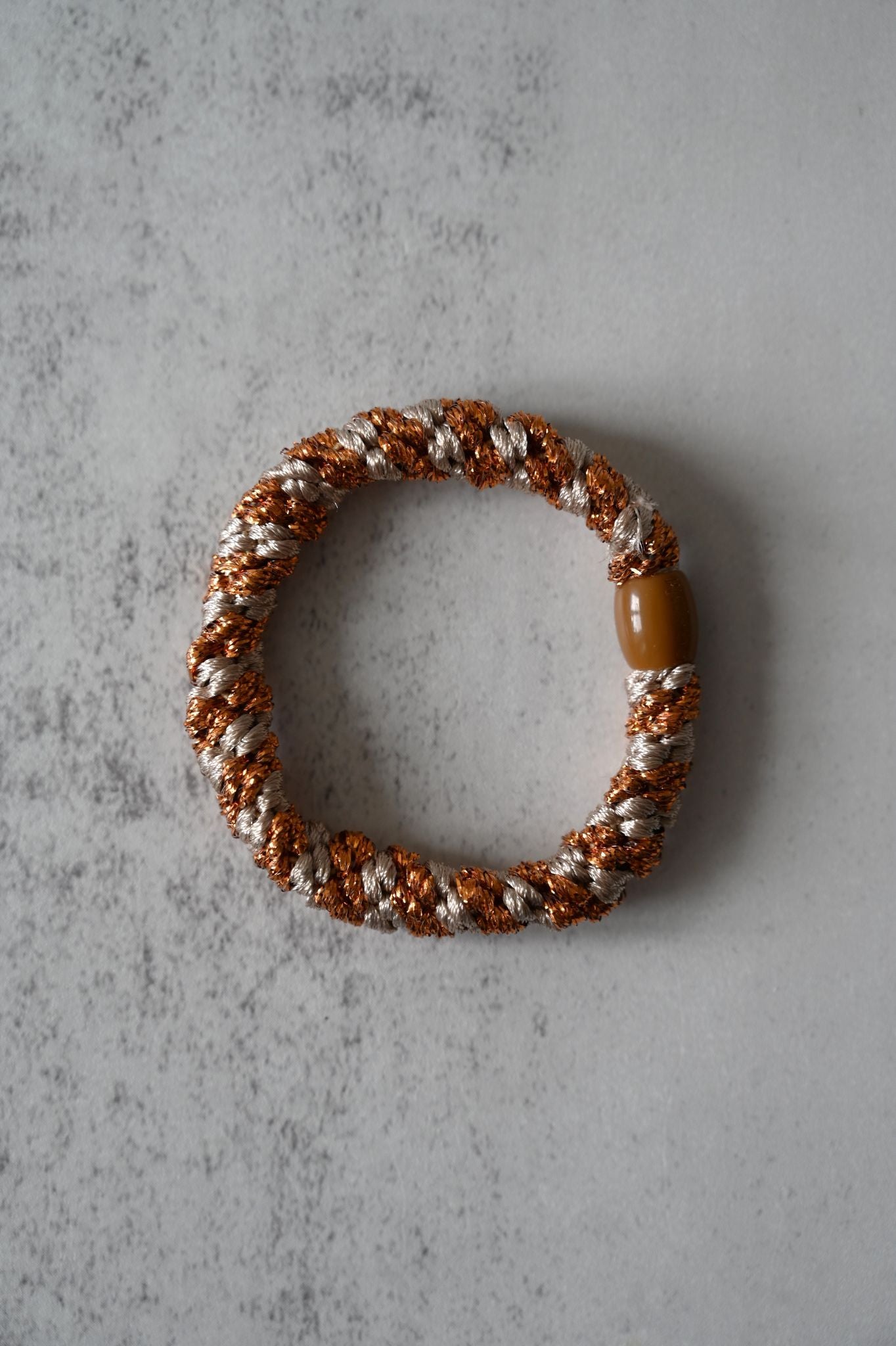 Hair tie with brown and white pattern on a gray surface