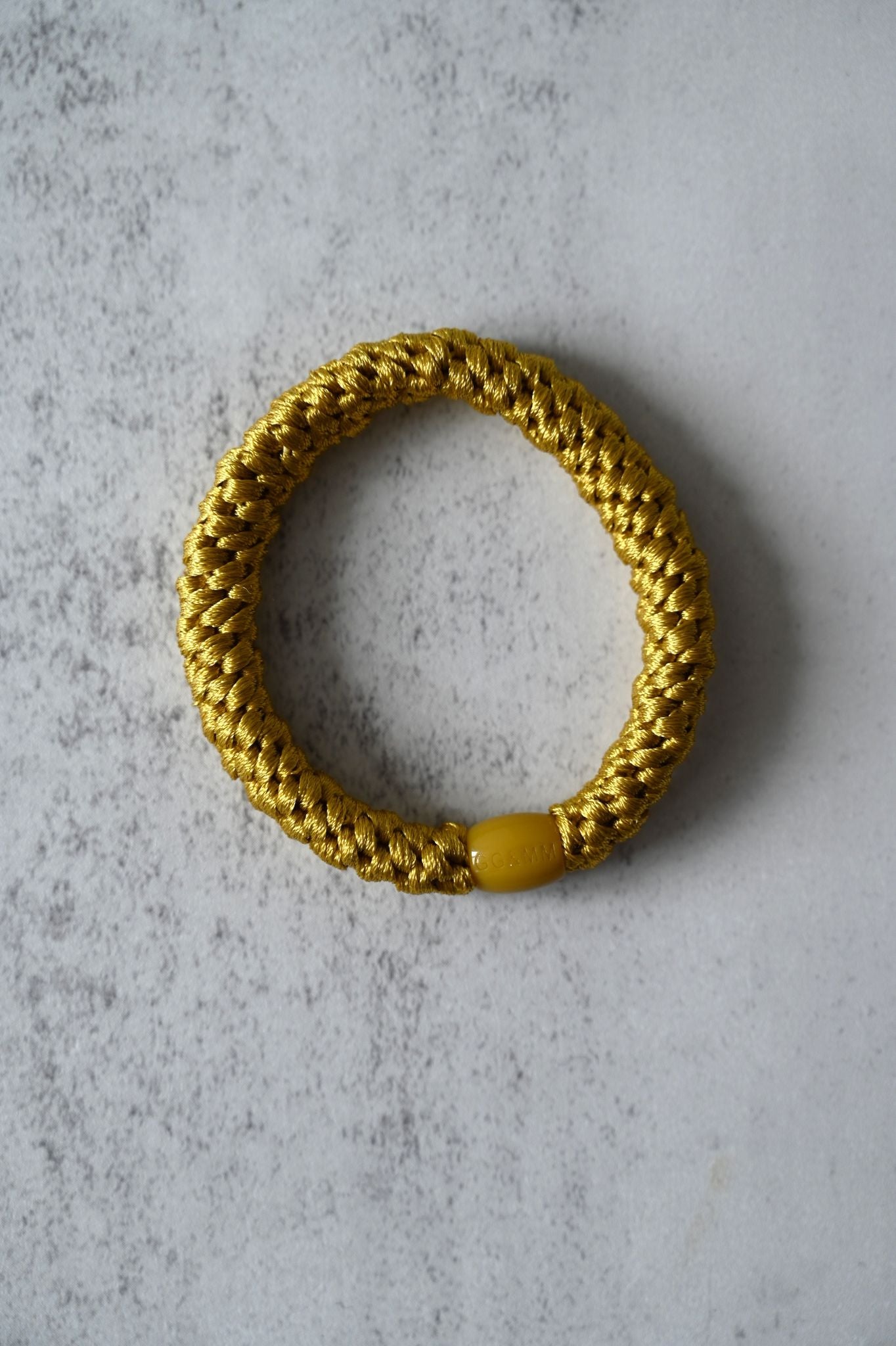 Gold hair tie on a textured gray surface
