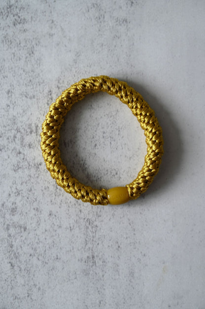 Gold hair tie on a textured gray surface