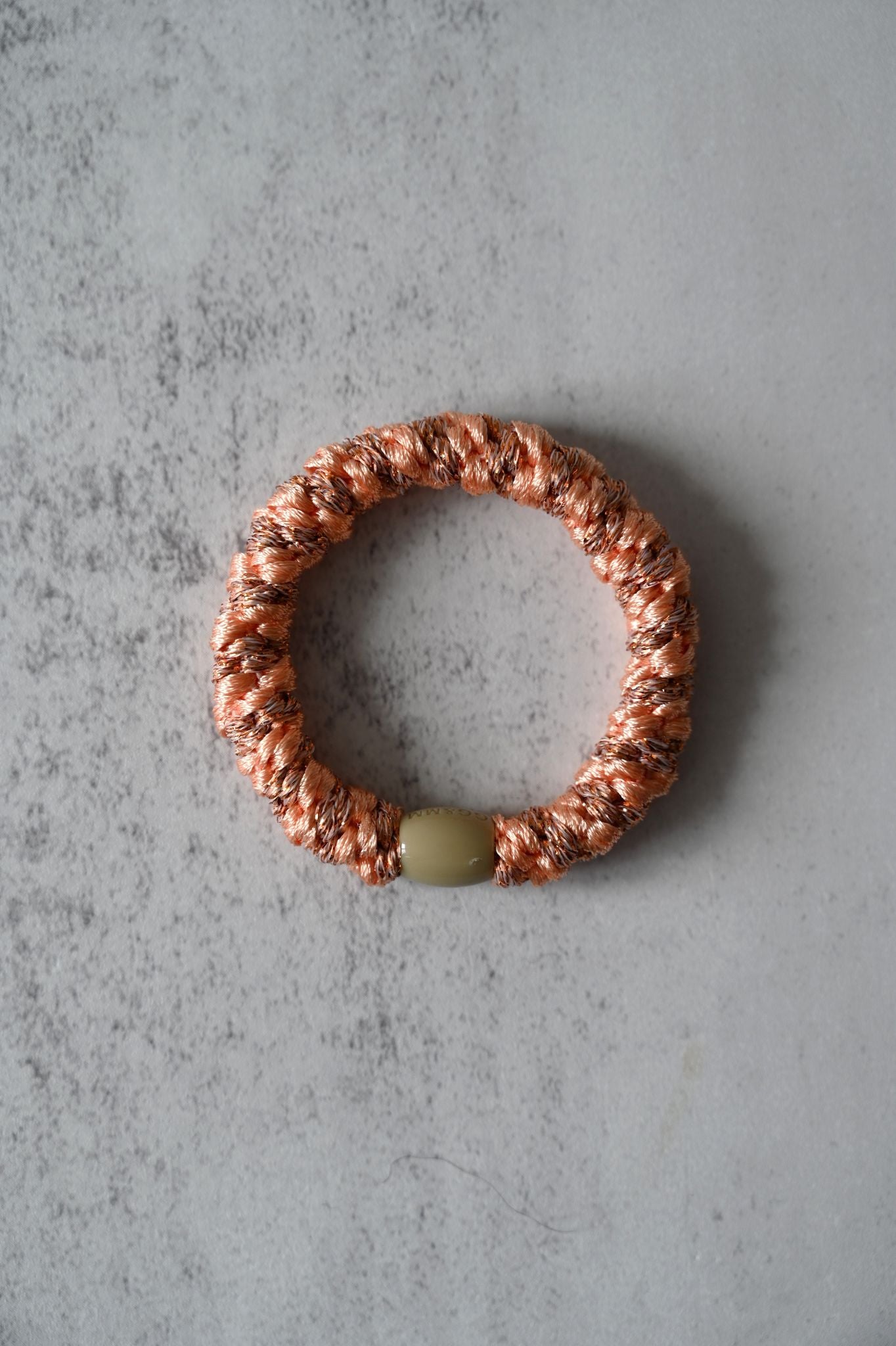 Hair tie with a green bead on a gray textured surface
