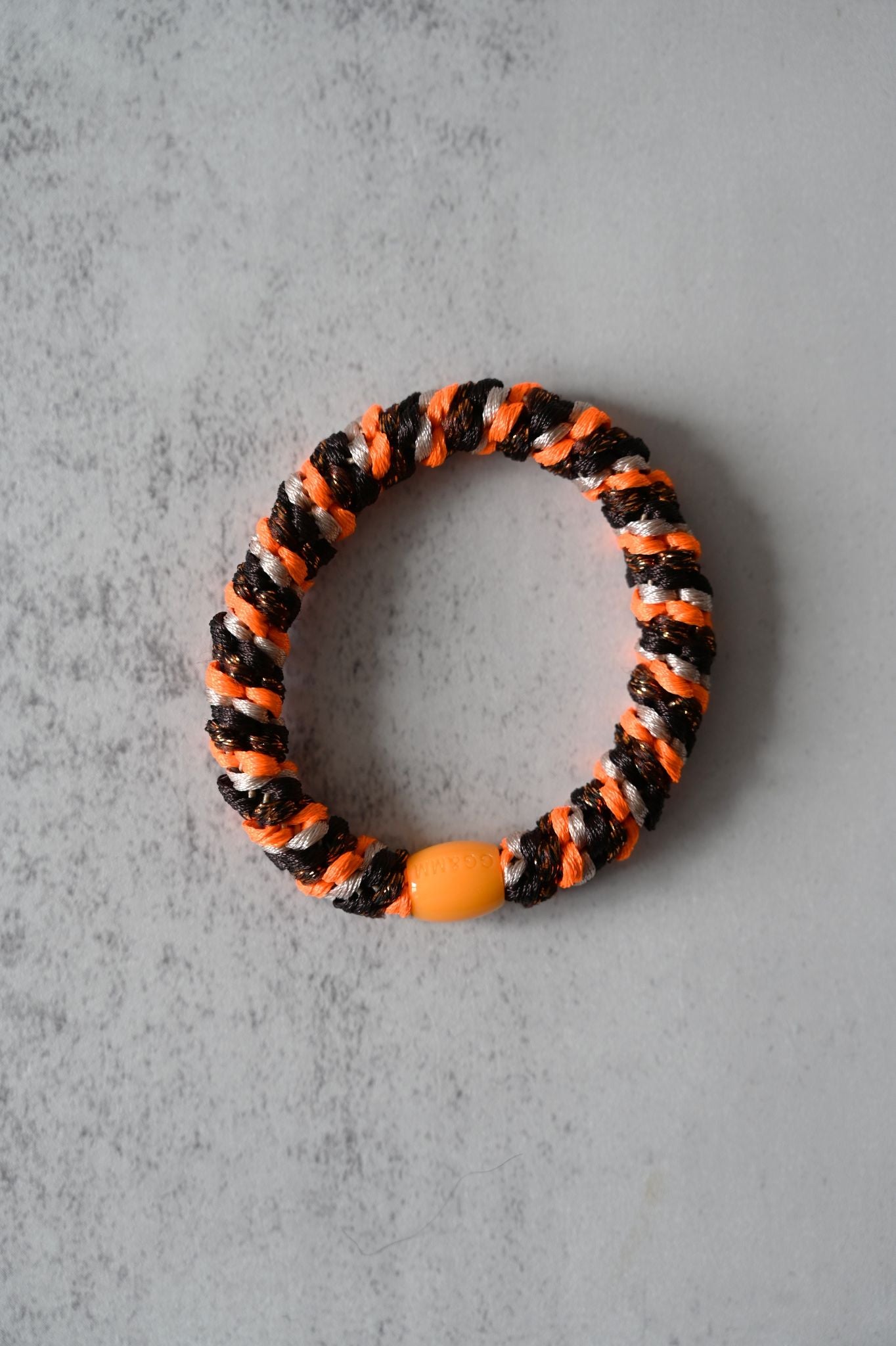 Hair tie with orange and black pattern on a gray background