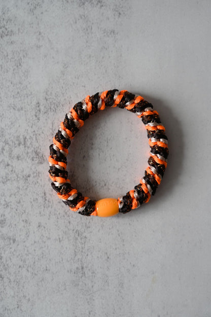 Hair tie with orange and black pattern on a gray background