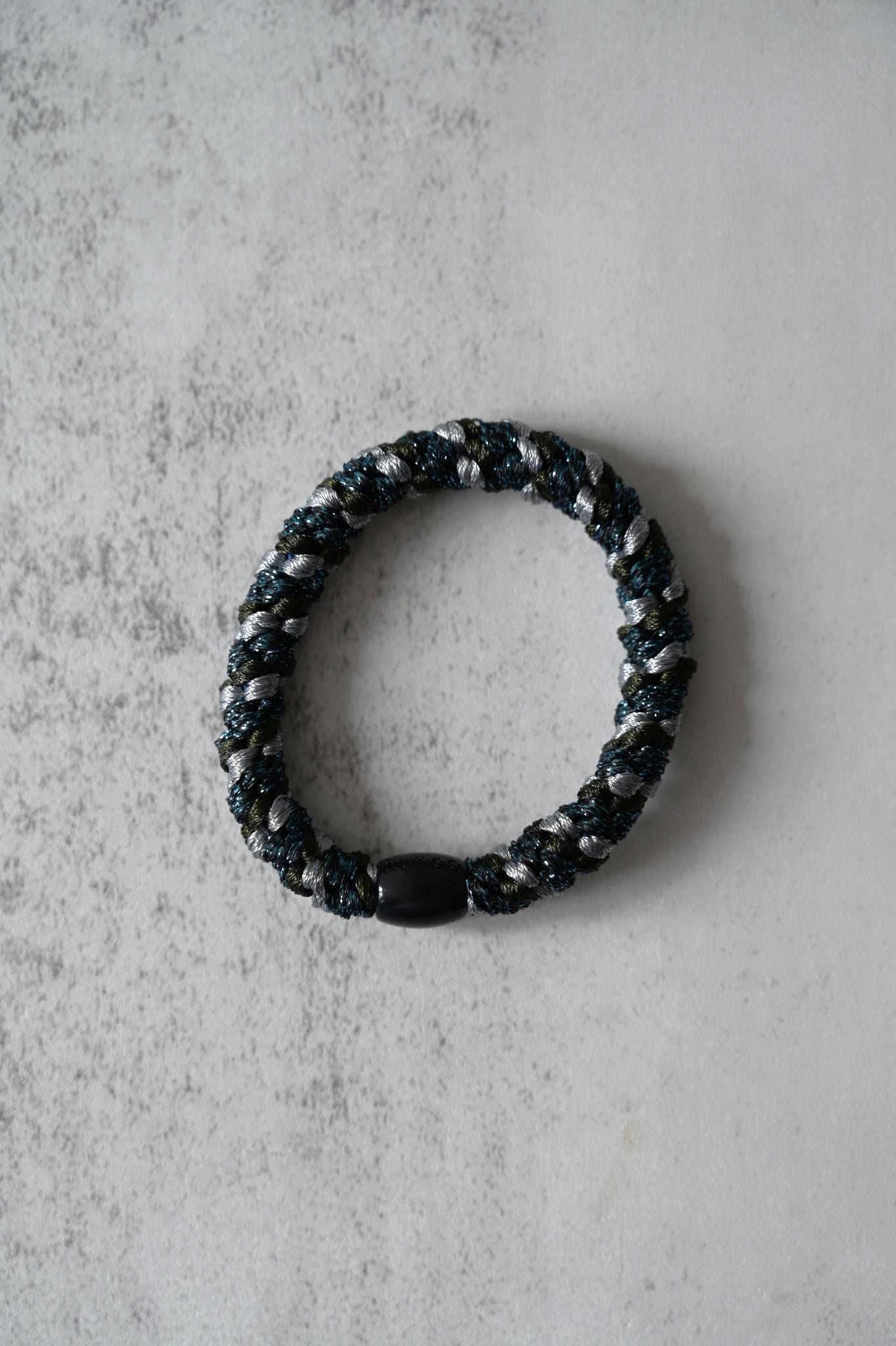 Black beaded Hair tie on a textured gray surface