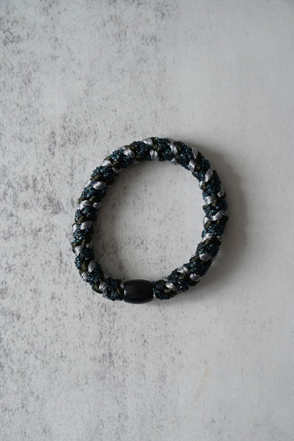 Black beaded Hair tie on a textured gray surface