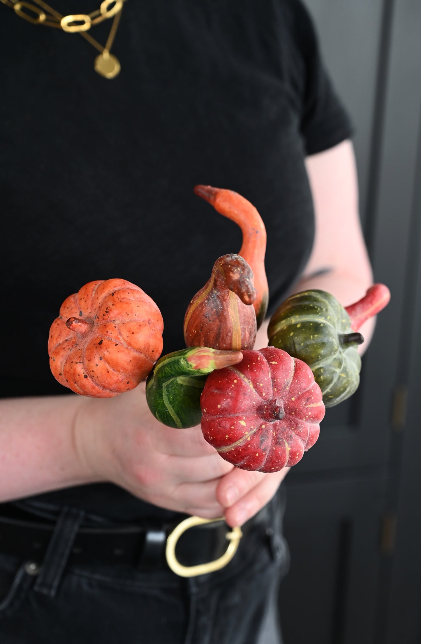 Person holding small gourds with a plain background