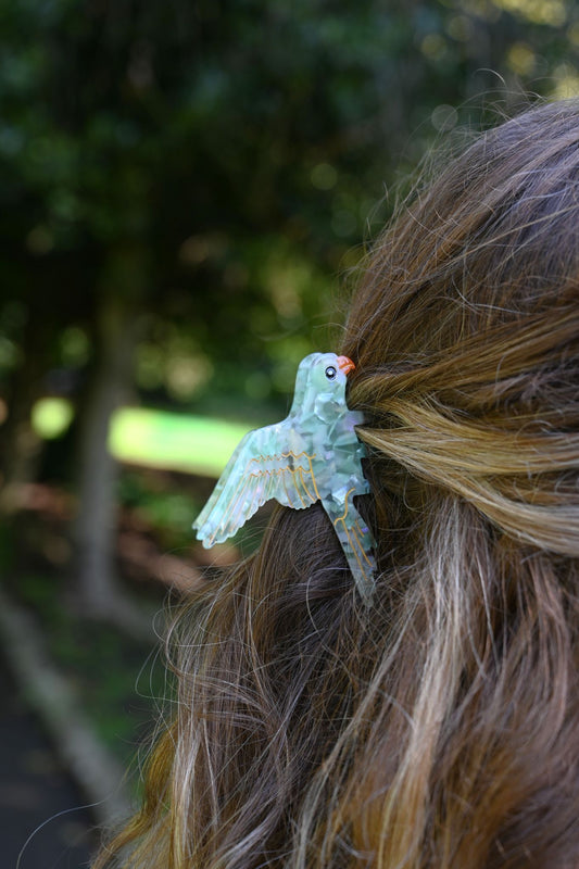 Hair clip shaped like a bird on a person's hair with a blurred natural background