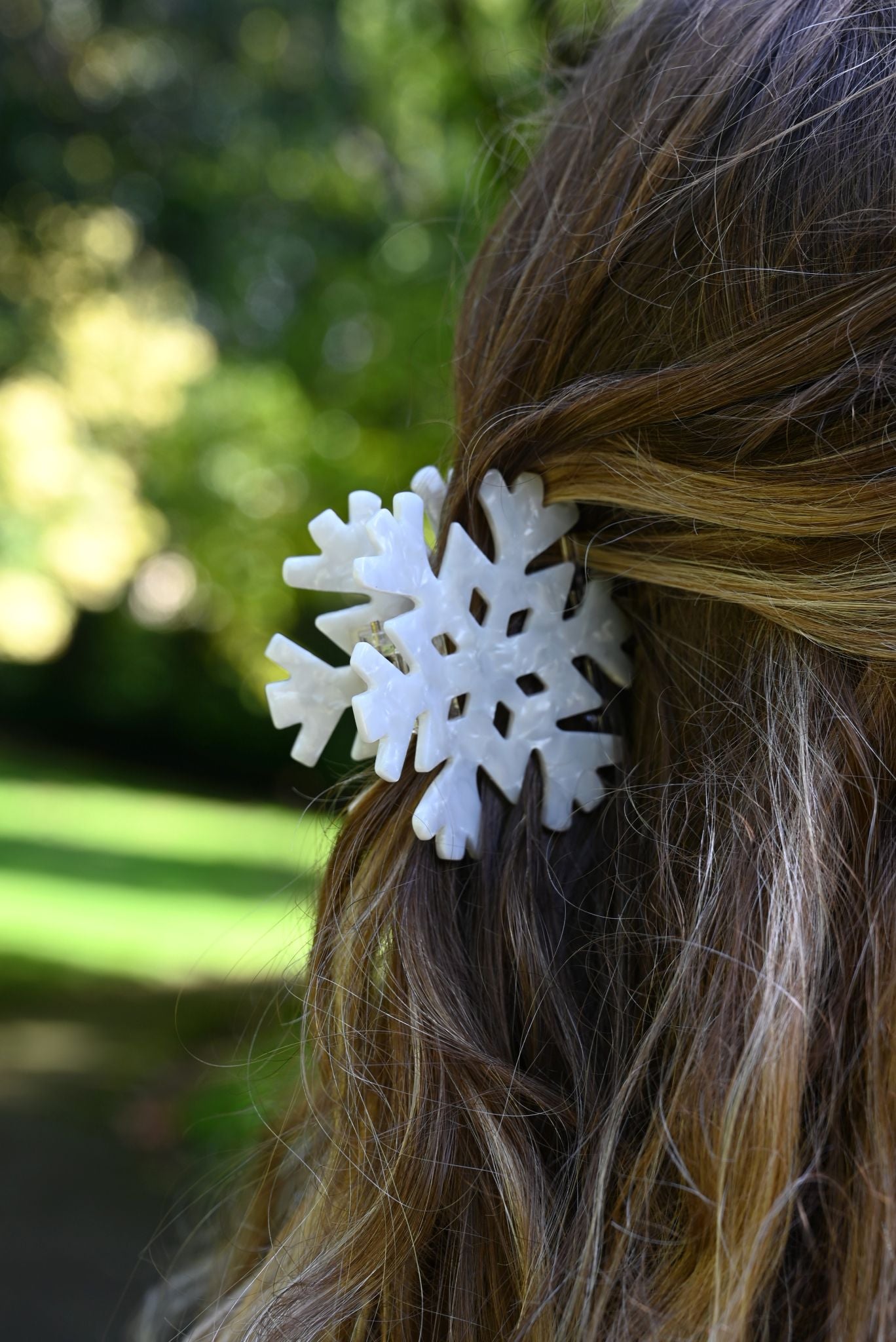White snowflake hair clip on a person's hair with a blurred green background