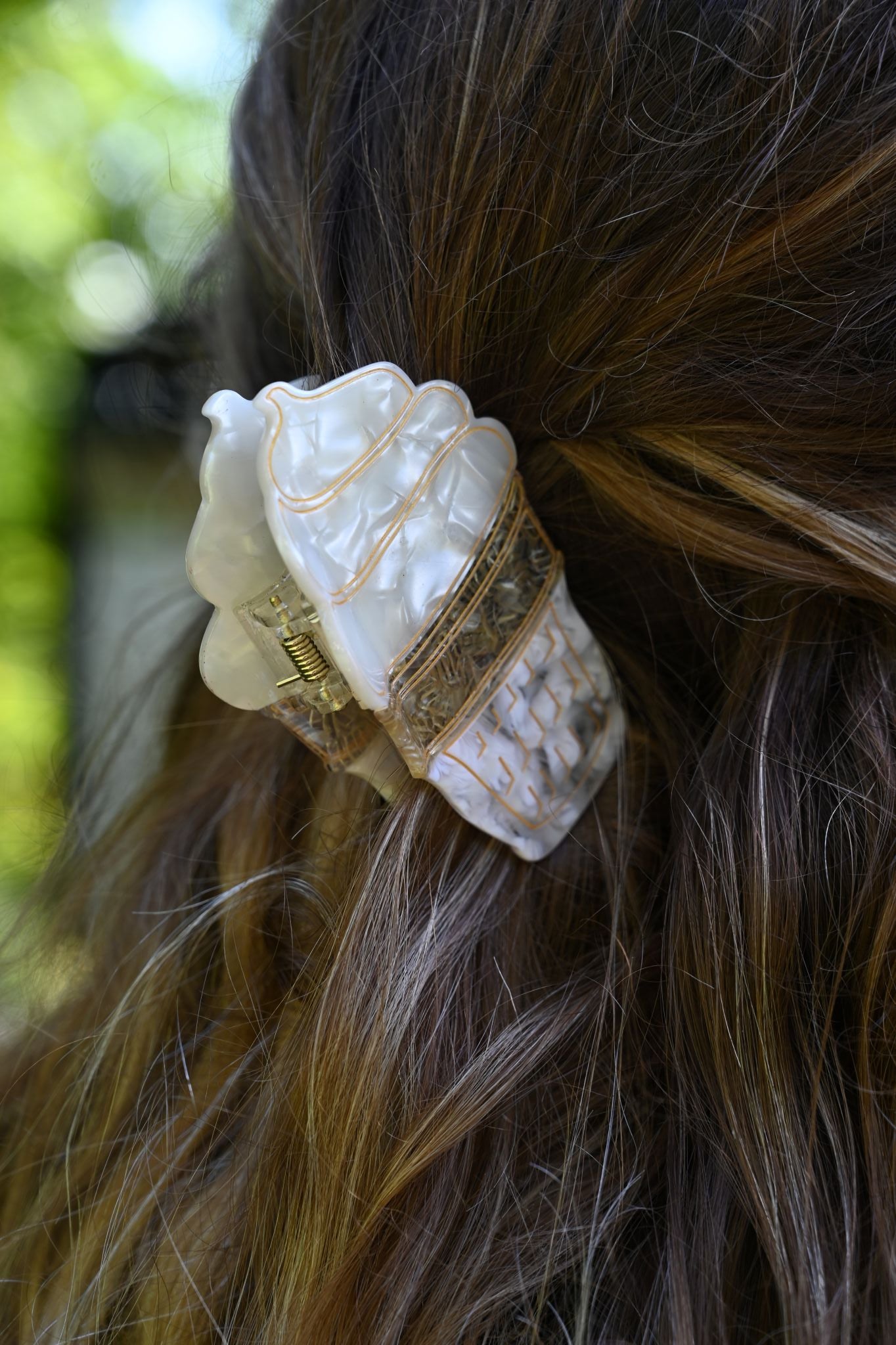 Close-up of a decorative ice cream hair clip in a person's hair with a blurred natural background