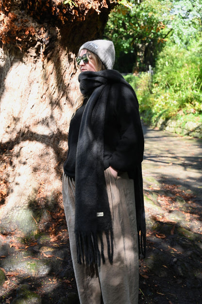 Person wearing a black scarf in a forest setting
