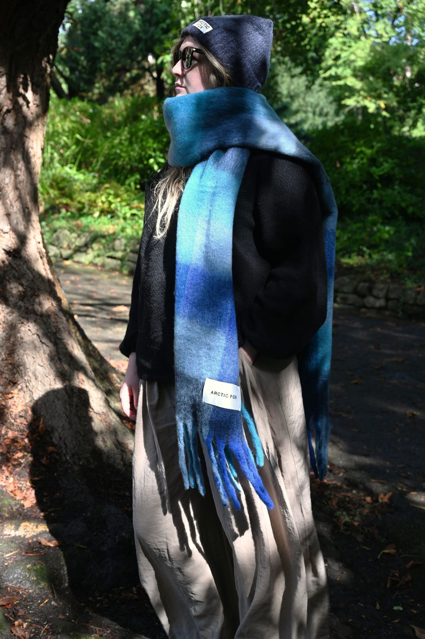 Person wearing a blue scarf and hat in a forest setting