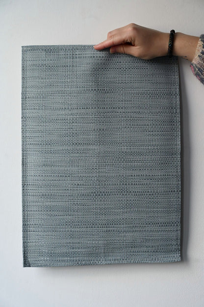 Person holding a blue woven placement against a white background