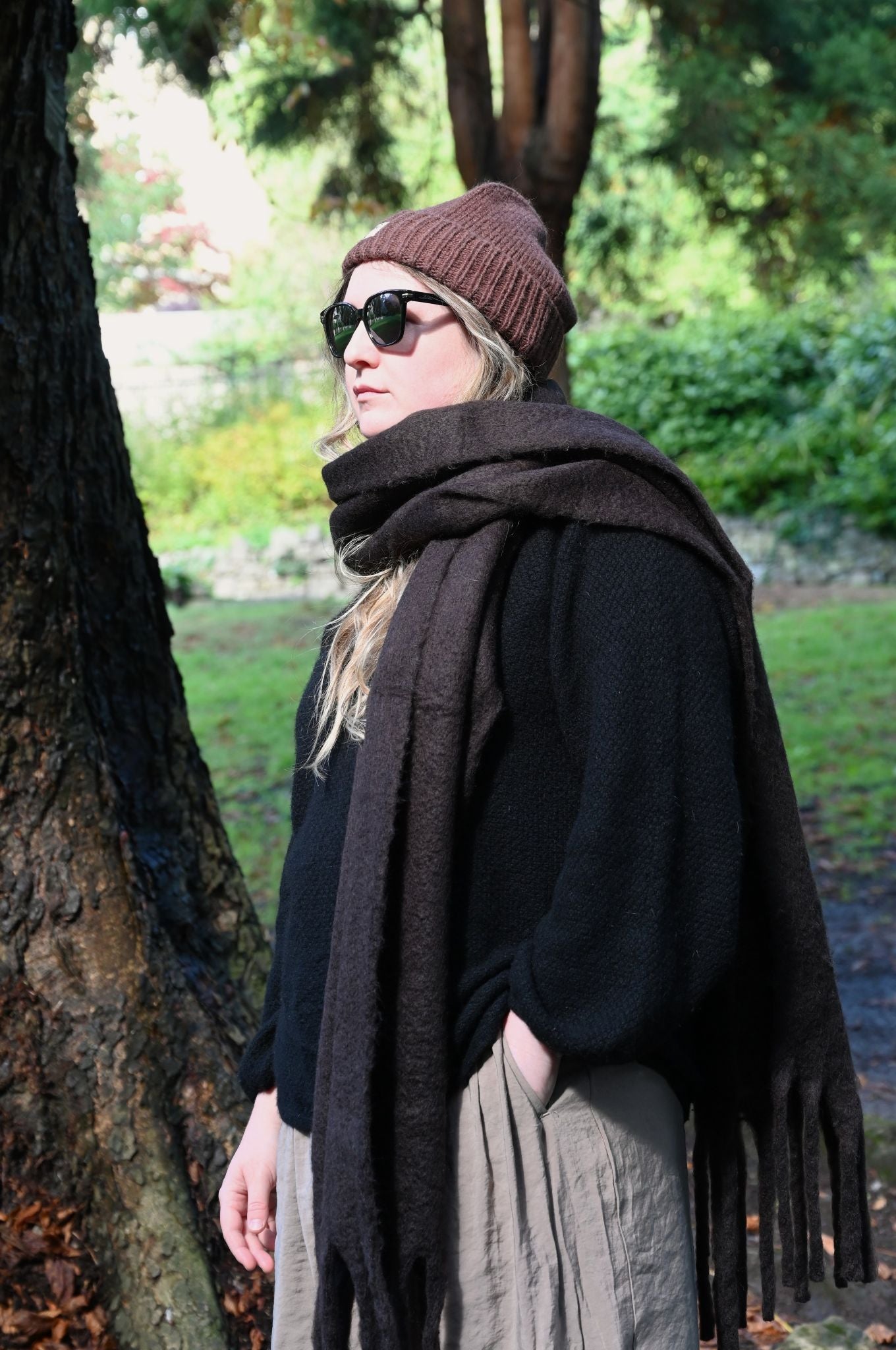 Person wearing a brown beanie and dark brown scarf in an outdoor setting