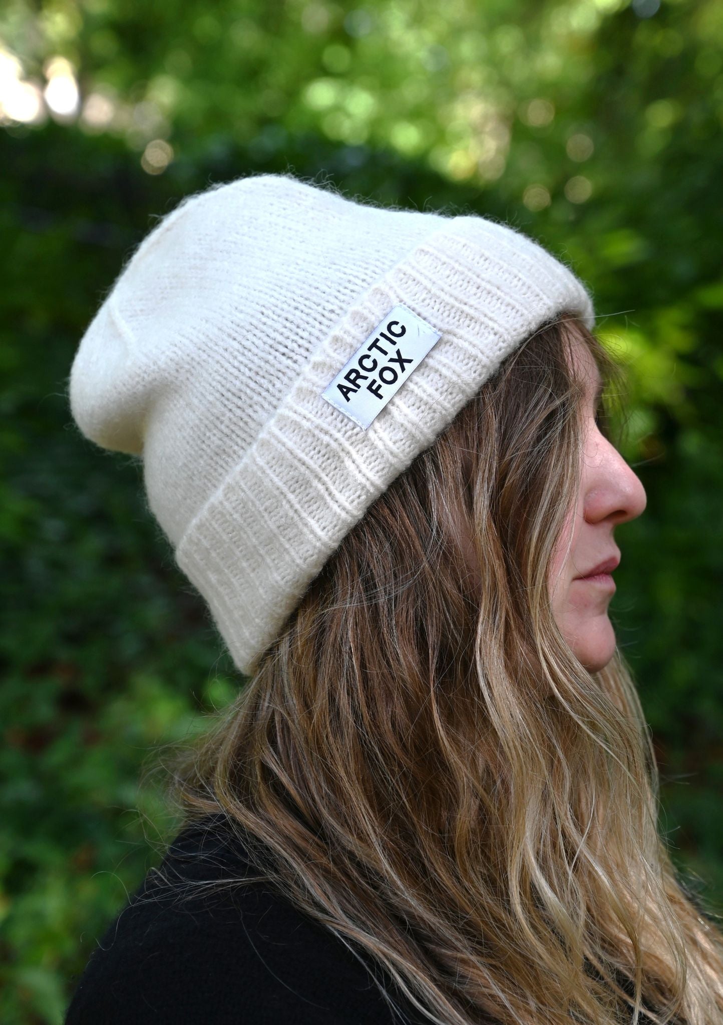 Person wearing a white beanie with 'Arctic Fox' logo against a green background