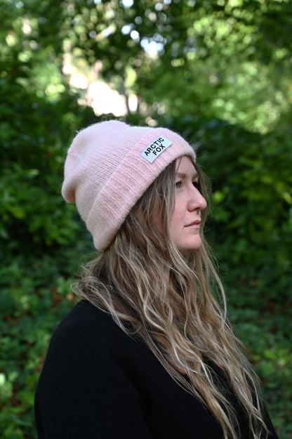 Person wearing a pink beanie with a logo outdoors
