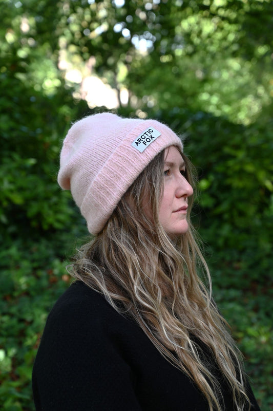 Person wearing a pink beanie with a logo outdoors