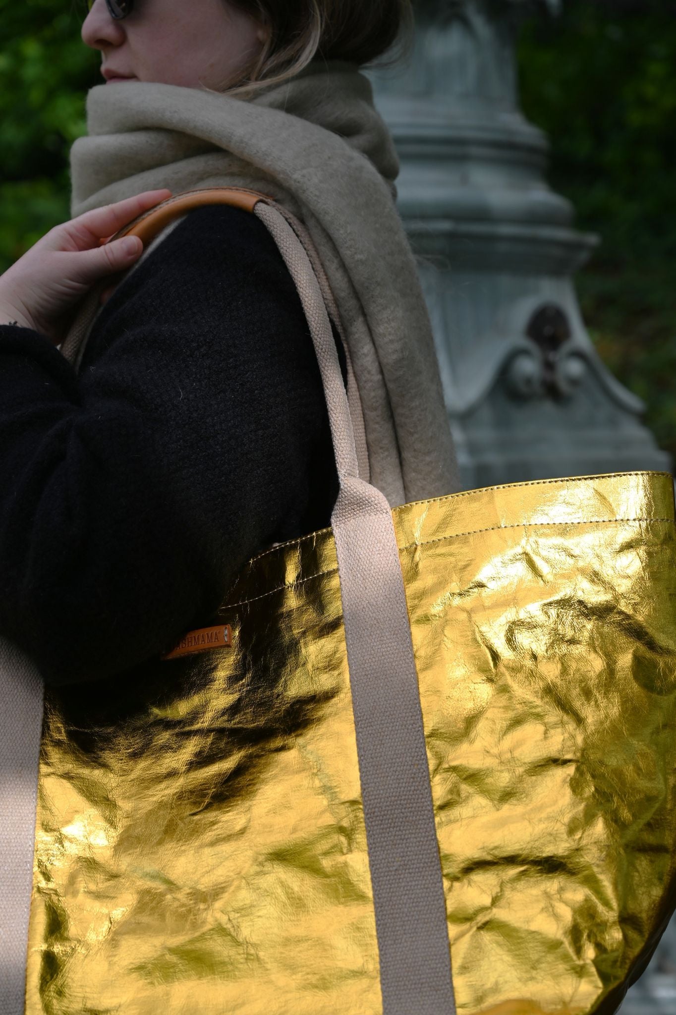 Person holding a gold tote bag with a blurred background