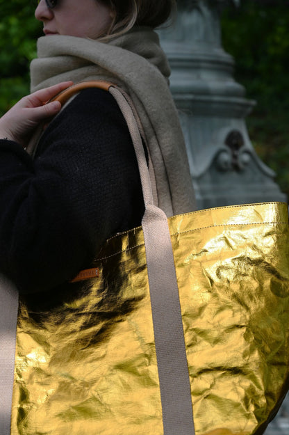 Person holding a gold tote bag with a blurred background