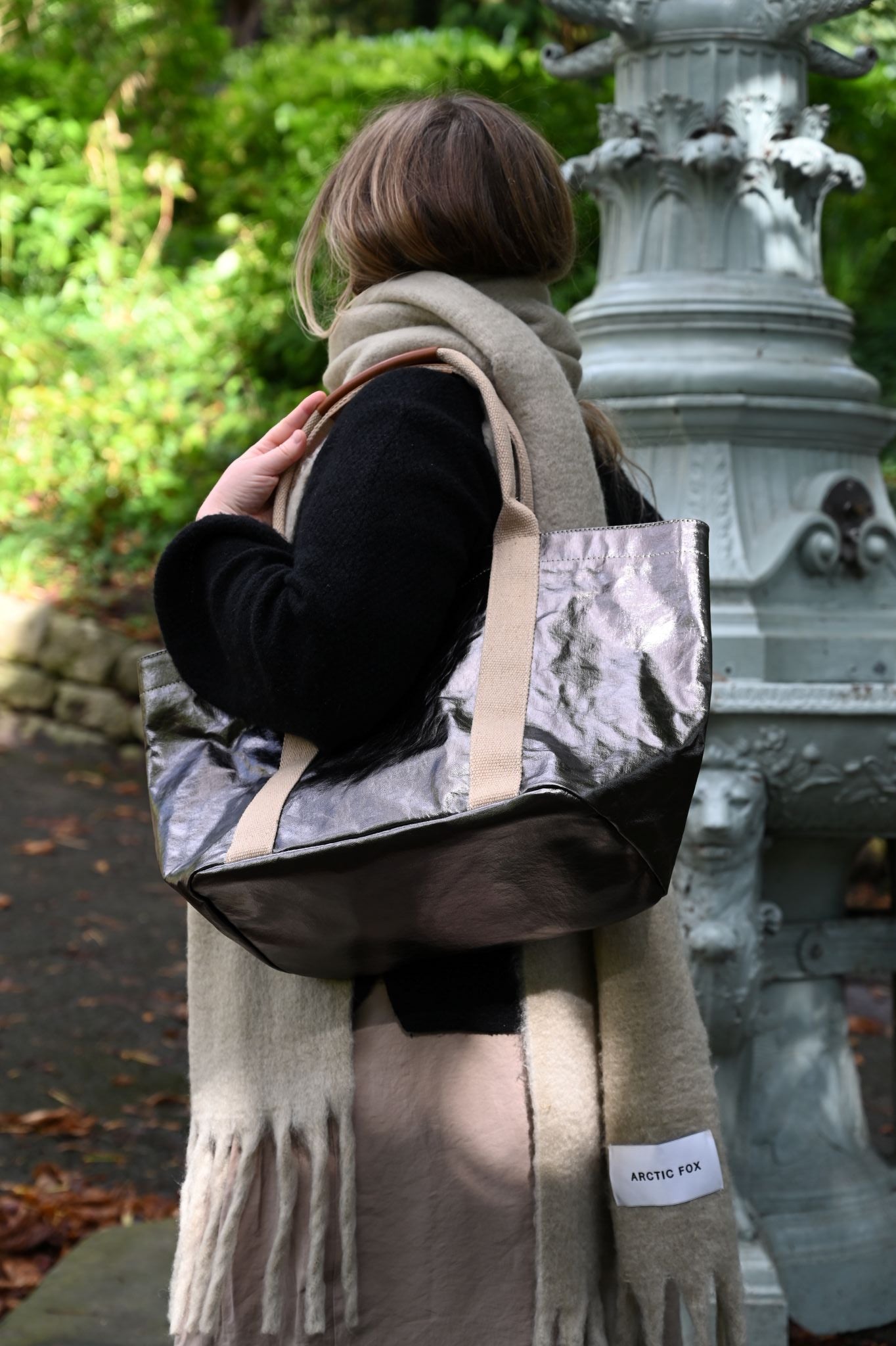 Person holding a small gunmetal tote bag with a blurred background