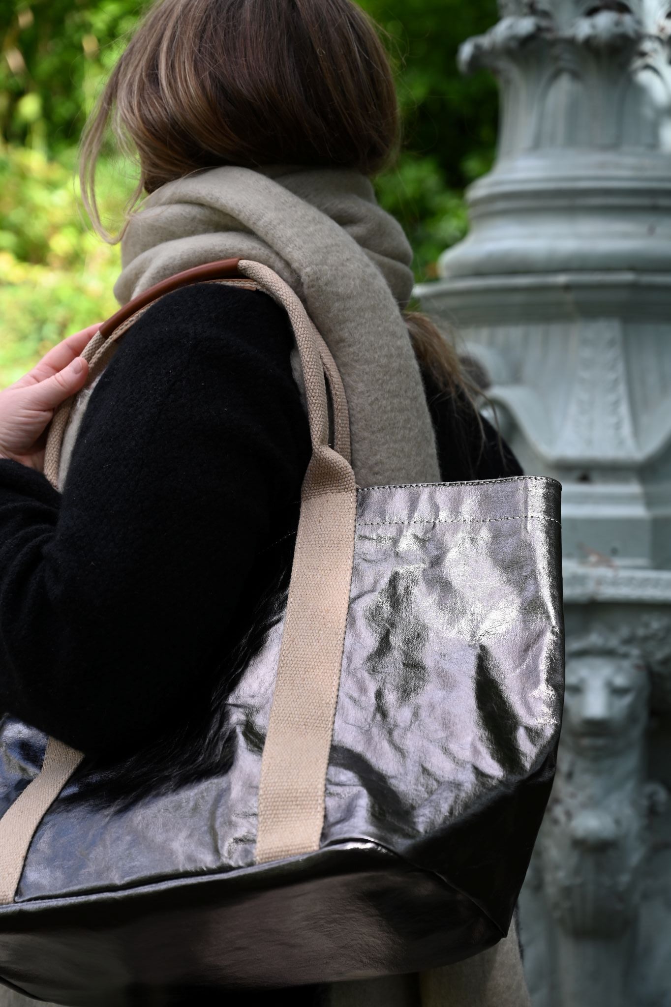 Person carrying a small gunmetal tote bag, in a blurred background