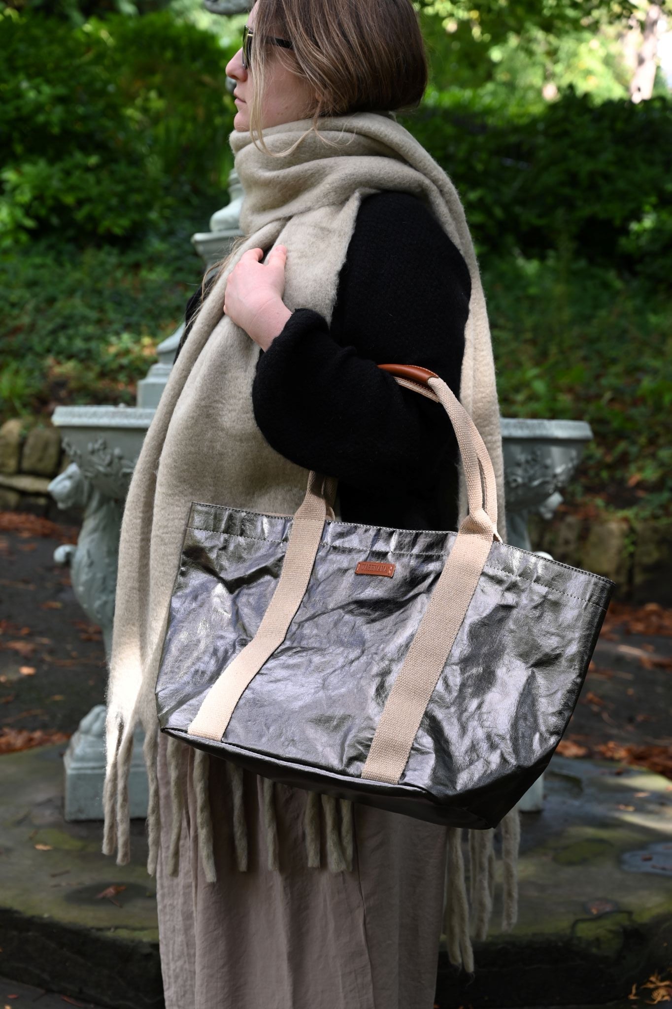 Person holding a small gunmetal tote bag, in the outdoors.